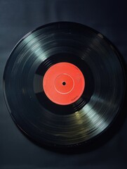 Fototapeta premium A black record with a red circle in the middle. The record is old and worn