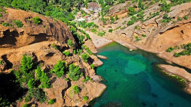 Aerial view of Tourist attraction beach, people enjoying summer vacation in Parc du Mugel, France. Snug Cove framed by rugged cliffs, with calm swimming off a pebble beach, and turquoise clear water.