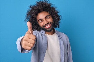 A joyful individual with curly hair enthusiastically gives a thumbs up, radiating positivity in a...