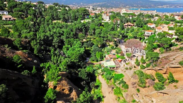 Aerial view of Tourist attraction beach, people enjoying summer vacation in Parc du Mugel, France. Snug Cove framed by rugged cliffs, with calm swimming off a pebble beach, and turquoise clear water.