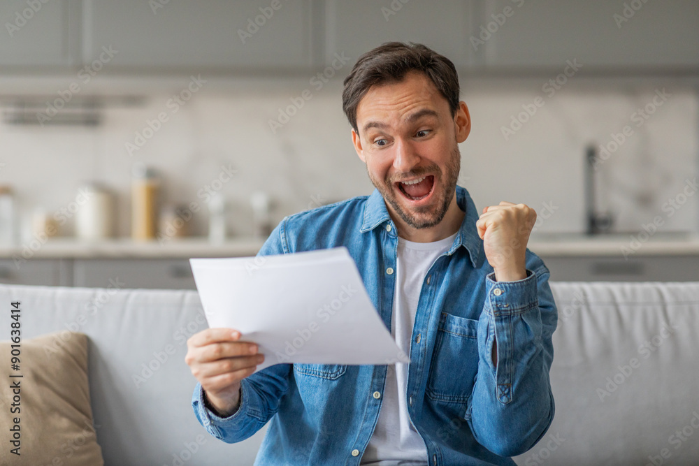 Poster A man holding a piece of paper and reading it with an excited expression. He has a big smile on his face and his right fist is clenched in the air. He appears to have just received some good news