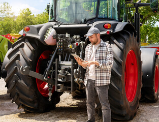 Agricultural equipment dealer or supplier. Caucasian man in plaid shirt stands next to tractor and...