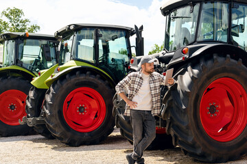 Agricultural equipment dealer or supplier. Caucasian man in plaid shirt stands next to tractors and...