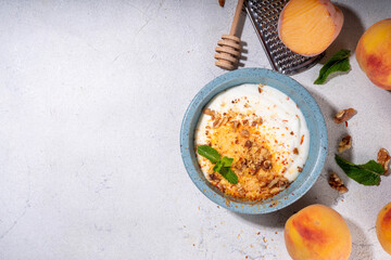 Frozen Shaved Peaches and Cream Dessert, Healthy summer snack with cream or yogurt and shaver frozen peach fruits, with nuts, honey and mint, copy space