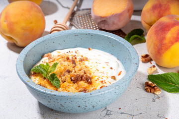 Frozen Shaved Peaches and Cream Dessert, Healthy summer snack with cream or yogurt and shaver frozen peach fruits, with nuts, honey and mint, copy space