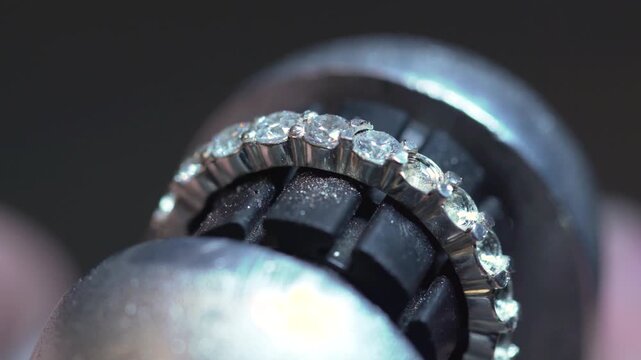 A jeweler, using a special machine, inlays a wedding ring made of gold, silver or other precious metals with diamonds in the jewelry manufacturing and processing workshop