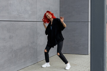 Happy positive emotional dancer curling in dance. Woman with red hair dancing on urban street, on...