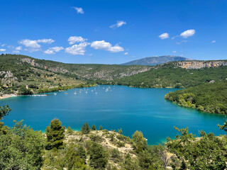 Stunning view from above of the beautiful alpine lake Lac de Sainte-Croix and green mountains in Provence, France