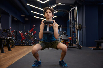 Handsome sporty young boy enjoying fitness activity at gym