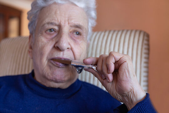 wrinkled hand of old person holds chelate bar to eat