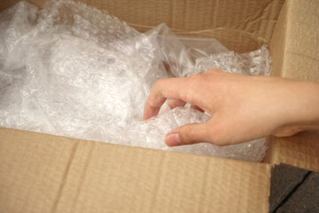 A person unboxing a cardboard box with bubble wrap inside of it. Close up.