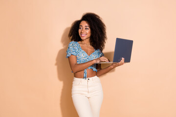 Photo of charming positive woman wear blue top chatting modern device looking empty space isolated beige color background