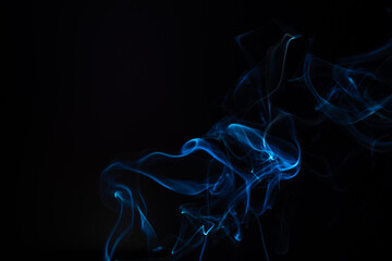 Blue smoke isolated on a black background. A thin curved line of smoke, steam from a burnt candle to overlay on your photos