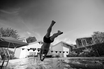 Black and white photo. Man, swimmer dives into pool outdoor with streamlined body, demonstrating...