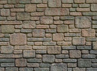 Close up design texture showing a colourful section of wall constructed with irregular stone bricks, of different sizes.