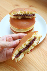 Hand Holding Mouthwatering Split Dorayaki, a Japanese Pancake with Azuki Red Bean Paste Filling