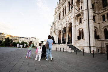 Family walking together in front of a historic European building in a city Budapest, Hungary.
