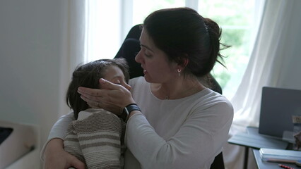 Concerned mother comforting her child who got hurt in the head, holding him gently, showing caring...