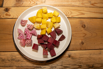 A plate of chopped up ingredient ready to make a delicious meal consisting of Fresh yellow and pink and white chioggia beets