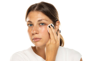 Portrait of a young woman removing her make-up on a white studio background