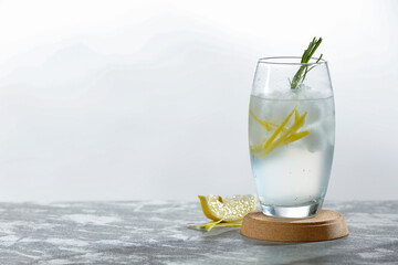 Glass of mocktail cold water drink with lemon and lemon peel and ice cubes. White background.