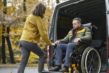 Female assistant helping a male person in a wheelchair with van transportation in an autumn park