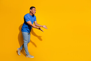 Naklejka premium Full size photo of pretty young male point hands hold empty space wear trendy blue outfit isolated on yellow color background
