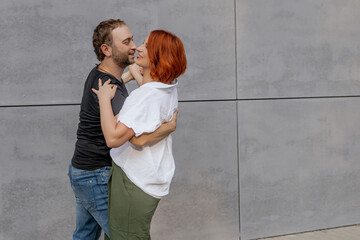 Happy dancers curling in dance in city. Romantic couple, woman with red hair and man in dark...