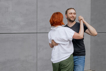 Happy dancers curling in dance in city. Romantic couple, woman with red hair and man in dark...