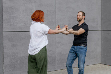 Happy dancers curling in dance in city. Romantic couple, woman with red hair and man in dark...