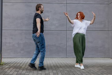 Happy dancers curling in dance in city. Romantic couple, woman with red hair and man in dark...