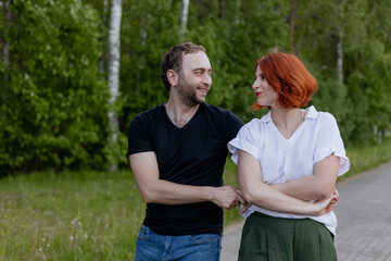 Happy dancers curling in dance in park. Romantic couple, woman with red hair and man in dark...
