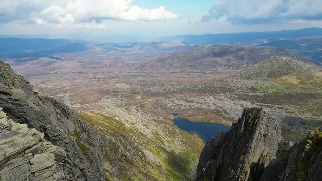 Aerial reveal of Loch Nagar and surrounding Cairngorms national park of Scotland landscape from mountaintop cliff viewpoint. 