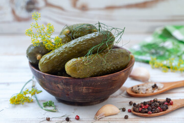 Bowl of tasty pickled cucumbers with spices and dill on light background. Marinated homemade pickled cucumbers. Healthy fermented food.