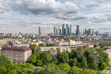 Panoramic view of residential and administrative buildings, the Moscow City district among green trees in the capital city of Moscow from a bird's eye view, aerial view in summer.