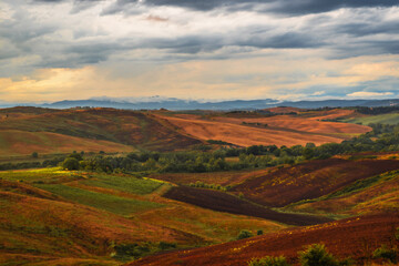 Naklejka premium Serene Toscany Rolling Hills Under Dramatic Clouds at Dusk in a Rural Italian Landscape