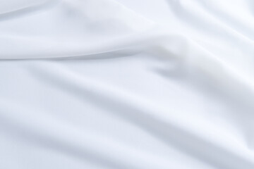 White fabric texture with a curve. Close-up soft fabric texture background with stylish, minimal, bright, crumple, fashionable textiles for wallpaper. Texture background of wavy white fabric.
