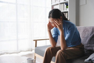 Tired overworked young woman feeling strong headache, massaging temples, suffering from migraine at home