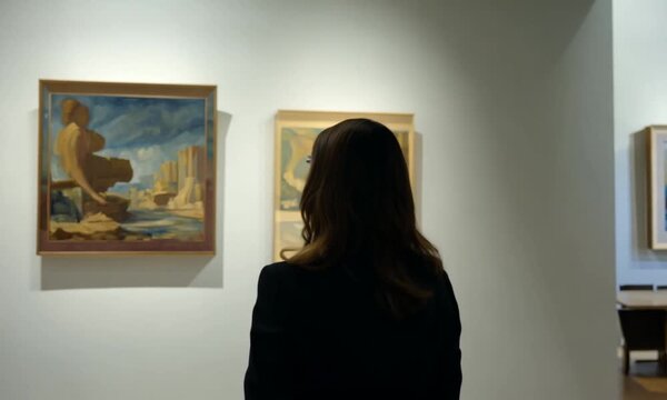 woman walking through museum viewing the paintings