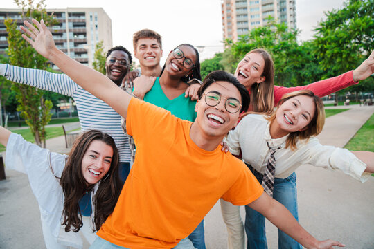 Group of international friends having fun, gesturing and looking at camera together. Student people smiling on a friendly meeting outside. Young teenagers bonding and celebrating on a social gethering