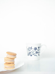 Minimalist composition with biscuits and a mug of milk on white background. Front view.