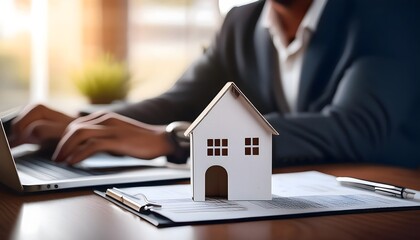Realtor working on a laptop with a house