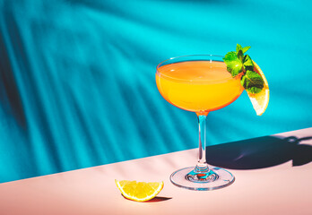 Yellow alcoholic cocktail drink with rum, liquor, grapefruit and lemon juice. Blue background, hard light and shadows