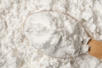Background of potato starch with a spoonful of potato starch from above.
