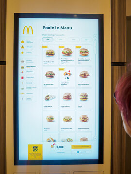 Woman ordering food using a self ordering kiosk at mcdonalds fast food restaurant