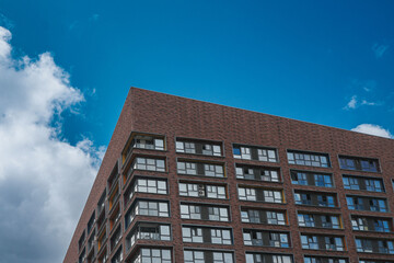 A fragment of a residential building against the background of a blue sky and clouds.