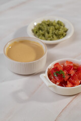 Red, yellow and green sauce in bowls on light background