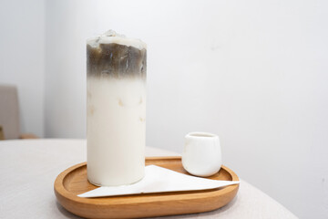 Iced roasted green tea with milk on wooden tray on white table
