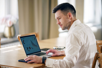 A focused professional works diligently on his laptop in a sunlit office, exemplifying dedication.