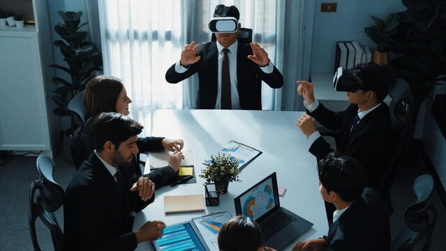 Top view of manager working on laptop and sending data analysis to business people by using VR glass headset while diverse team planning marketing strategy and looking at financial graph. Directorate.